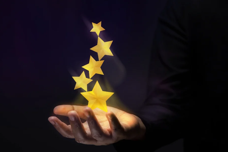 A close up of a man's hand holding five glowing floating stars