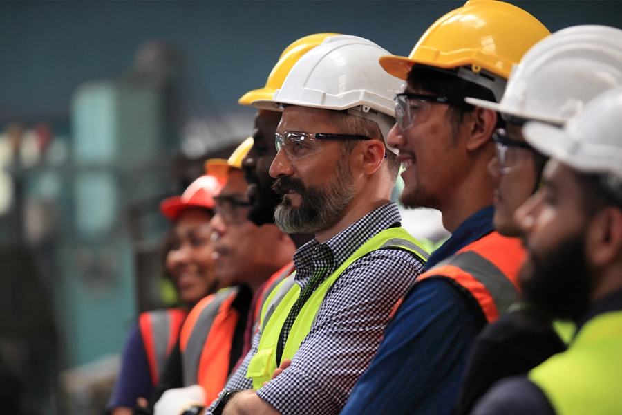 A group of men in hard hats stand in a line listening to instructions