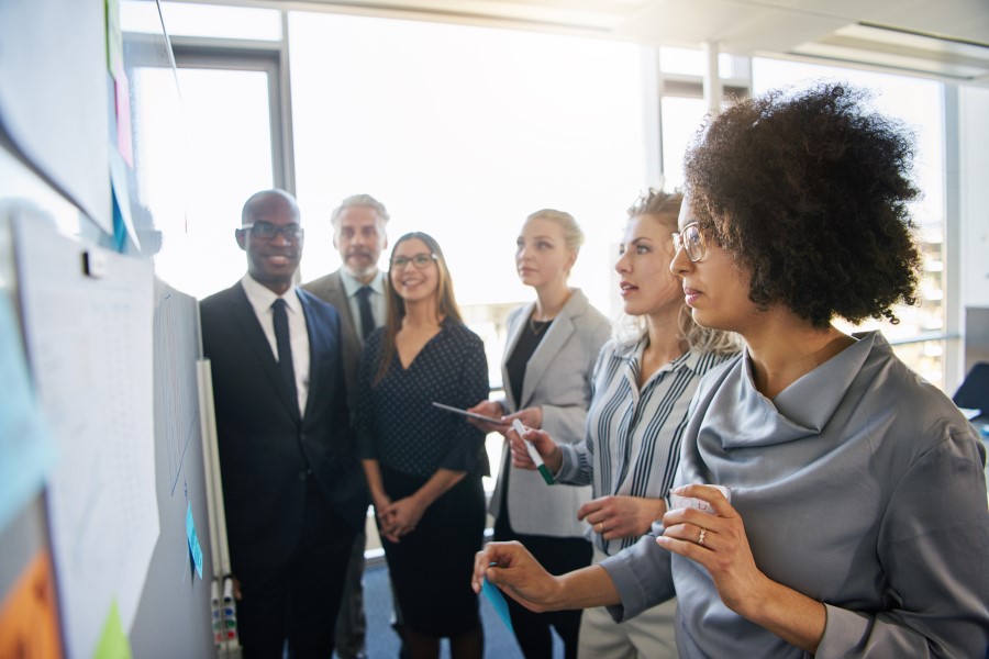 A group of business people study a white board in a conference room