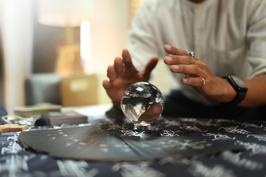 Hands hover over a crystal ball