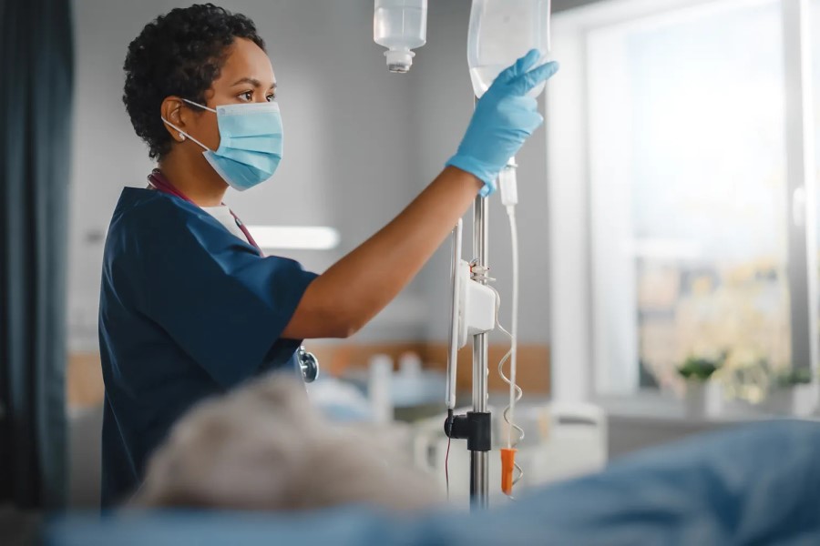 A nurse checks a patient's IV drip